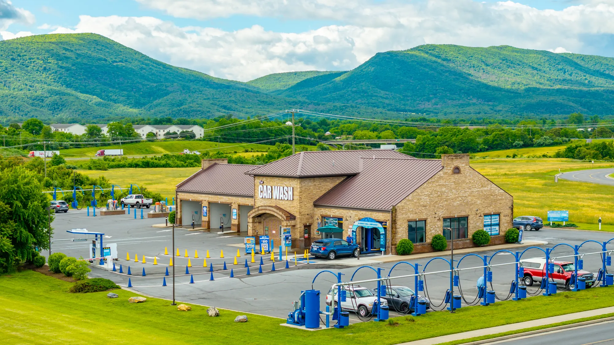 Aerial view of Woodstock Car Wash in Woodstock, Virginia, with the vacuum islands and the Blue Ridge mountains behind